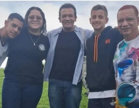 O ator com os alunos e o professor respons&aacute;vel pelo projeto